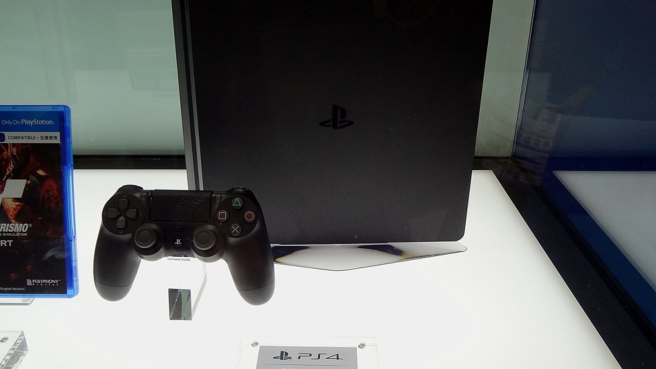Black PS4 Slim with a DualShock 4 controller on a display stand